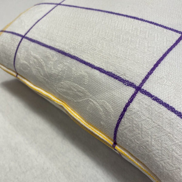 Seitenansicht mit Reißverschluss Kissen aus strukturiertem weißem Stoff mit zwei lila Längs- und vier Querstreifen, und jeweils 3 gelben Streifen an der Seite, gefolgt von mehreren lila Streifen